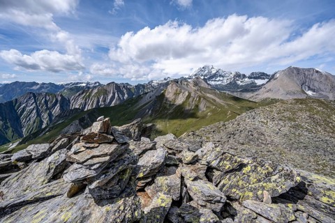 Cairn on the summit of Kastenegg, view of picturesque mountain landscape with snow-covered summit