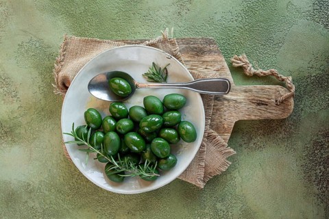 Chalkidiki olives, classic Greek green olive, on a plate, with a spoon, top view, no people