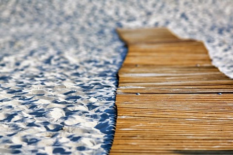 Empty wooden path on the sandy beach, wooden mat in the sand, barrier-free access,