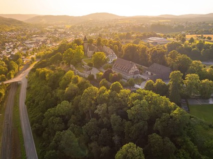 A village view from above with church and half-timbered houses on a tree-covered hill, event and