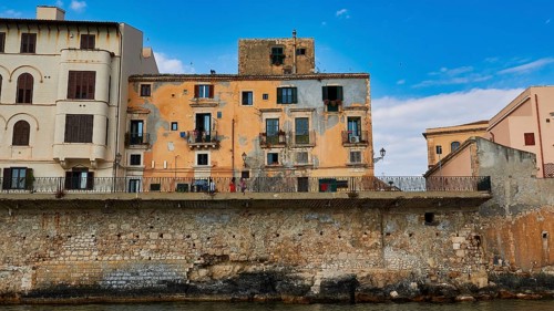 Houses with colourful facades and balconies along a stone seawall, boat trip around the island of