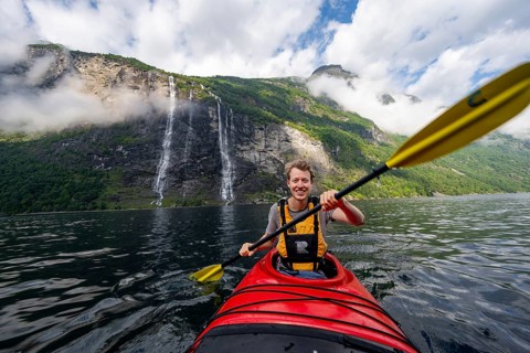 Kayak trip on the Geirangerfjord at the waterfall The Seven Sisters, Young man paddling in a kayak,