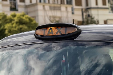 Illuminated taxi sign on top of a classic black cab in london, england, providing transportation