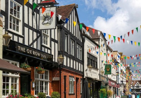 Bunting flags decorating buildings in historic street, The Ox Row Inn and shops, Butcher Row,