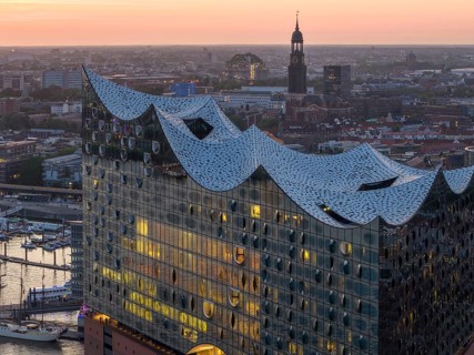 Aerial view of the Elbphilharmonie at sunset with illuminated windows and view over Hamburg and the