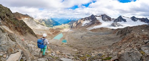 Mountaineer with helmet in high mountain landscape, view of blue glacial lakes, mountain peaks