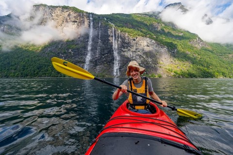 Kayak trip on the Geirangerfjord at the waterfall The Seven Sisters, Young man paddling in a kayak,