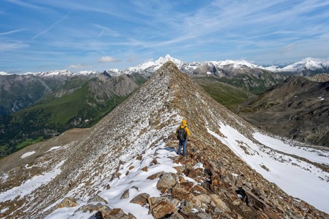 Mountaineer climbing to the summit of Böses Weibl, view of mountain landscape with snow-covered