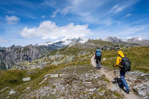 Mountaineers on a hiking trail, view of picturesque mountain landscape with snow-covered summit of