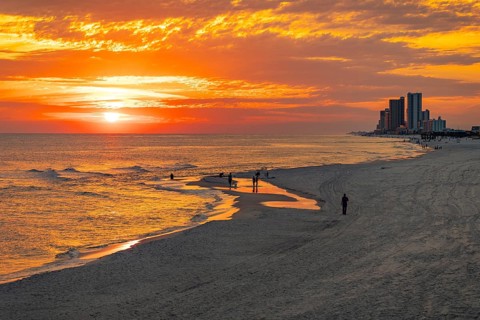 People playing and fishing on the beach at sunset on the Gulf of Mexico at Gulf Shores, Alabama