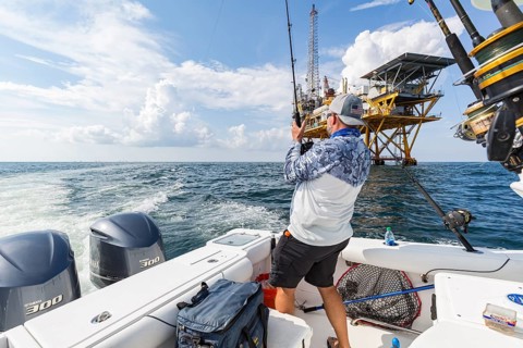 Fisherman trolling for fish near petroleum drilling rig in the Gulf of Mexico
