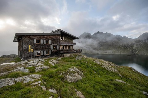 Mountain hut Wangenitzseehütte, cloudy mountain landscape with mountain lake Wangenitzsee, Wiener