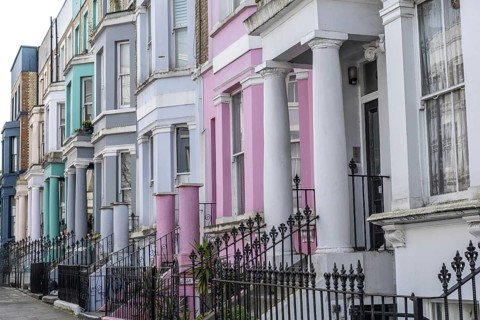 Pastel colored victorian terraced houses with ornate wrought iron fences create a picturesque