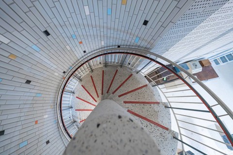 A modern spiral staircase with colourful tiles and bright lighting in a round shape, historical art