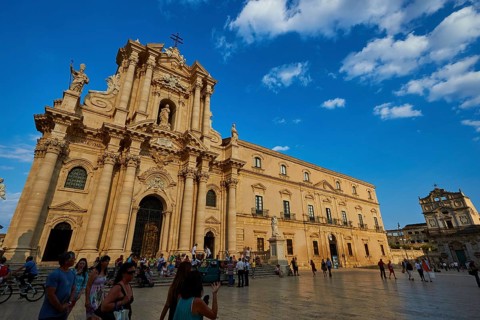 Cathedral of Syracuse, shot of the baroque cathedral from a distance with a busy square under a