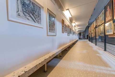 Long gallery corridor with paintings and a bench, historical art exhibition in the old swimming