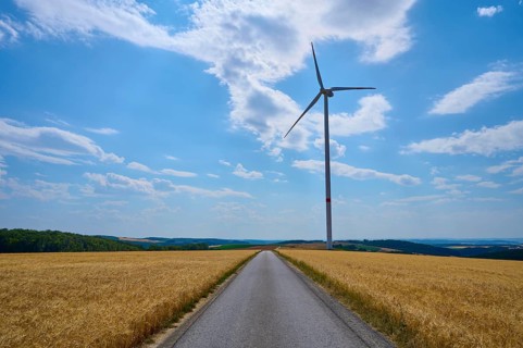 Rural landscape with wind turbine and cornfield and road under blue sky, summer, Retzstadt, Main