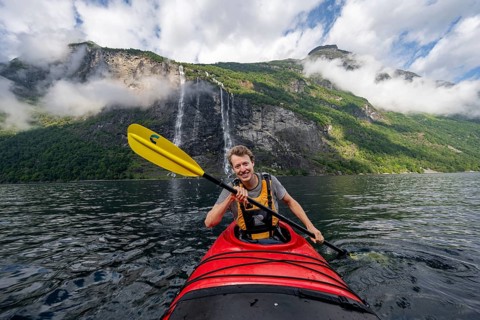 Kayak trip on the Geirangerfjord at the waterfall The Seven Sisters, Young man paddling in a kayak,
