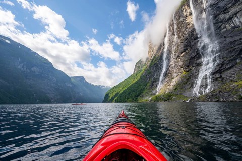 Kayak trip on the Geirangerfjord at the waterfall The Seven Sisters, tip of a red kayak in the