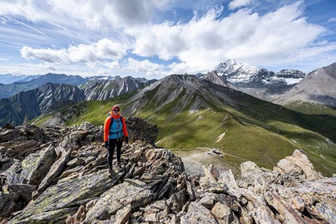 Mountaineer on the summit of Kastenegg, view of picturesque mountain landscape with snow-covered