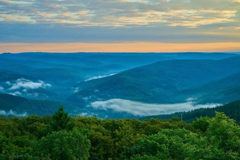 Green hills with forest at sunrise, fog in the valleys and peaceful sky, Katzenbuckel, Waldbrunn,