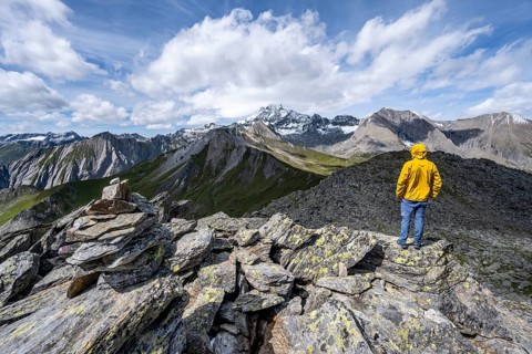 Mountaineer on the summit of Kastenegg, view of picturesque mountain landscape with snow-covered