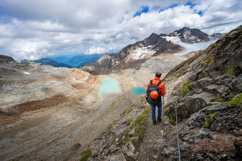 Mountaineer with helmet in high mountain landscape, view of blue glacial lakes, mountain peaks