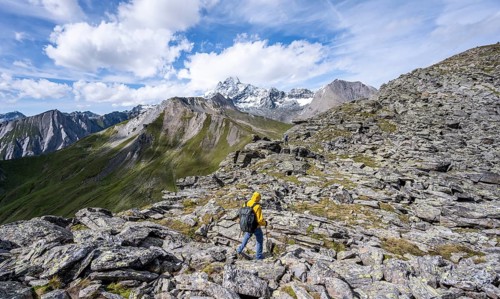 Mountaineer in boulder terrain, at the summit of Kastenegg, view of picturesque mountain landscape