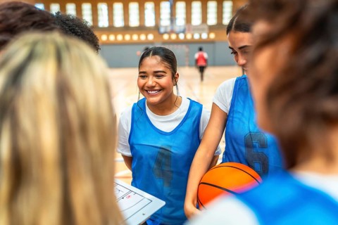Happy basketball players gathering in a gym, discussing game strategies and fostering teamwork