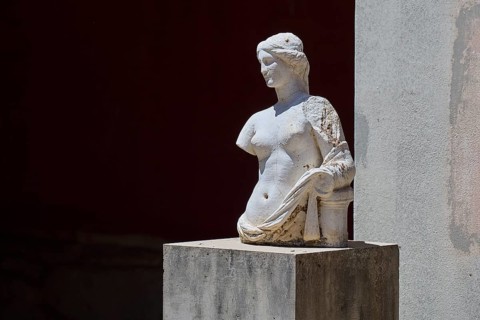 ©Udo Rein, An ancient marble bust with damaged arms stands on a pedestal in the shade, Aphrodite,