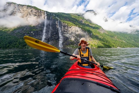 Kayak trip on the Geirangerfjord at the waterfall The Seven Sisters, Young man paddling in a kayak,