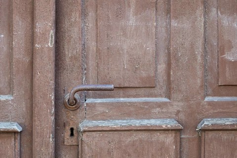Weathered brown wooden door with rusty door handle and visible texture, Bad Bergzabern, Southern