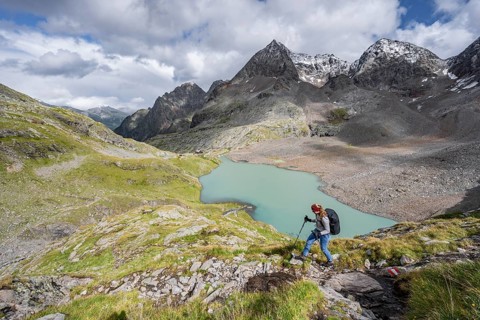 Mountaineer on hiking trail in mountain landscape, view of turquoise-blue mountain lake Großer