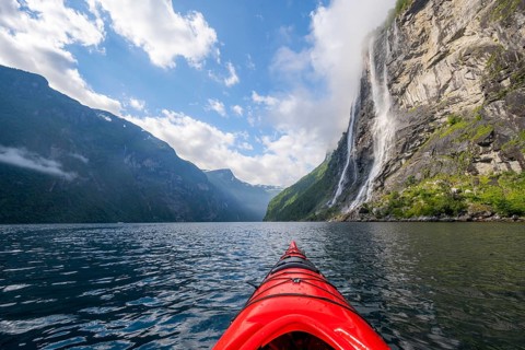 Kayak trip on the Geirangerfjord at the waterfall The Seven Sisters, tip of a red kayak in the