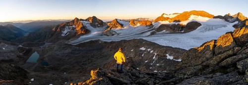 Mountaineers in front of a picturesque high mountain landscape at sunrise with alpenglow, blue