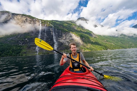 Kayak trip on the Geirangerfjord at the waterfall The Seven Sisters, Young man paddling in a kayak,