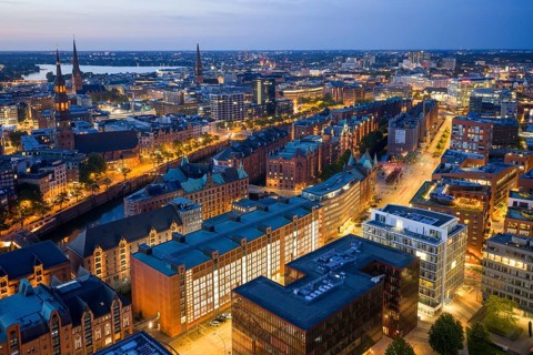 Aerial view of the Speicherstadt Hamburg at blue hour with churches and Alster in the background,