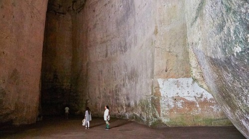 Cave Ear of Dionysus, Large rock cave with several people exploring the dark surroundings, Neapolis