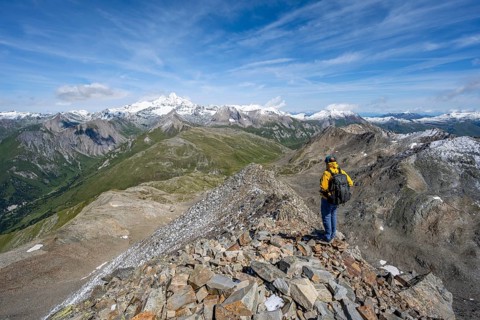 Mountaineer at the summit of Böses Weibl, view of picturesque mountain landscape with snow-covered