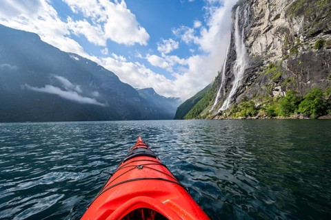 Kayak trip on the Geirangerfjord at the waterfall The Seven Sisters, tip of a red kayak in the