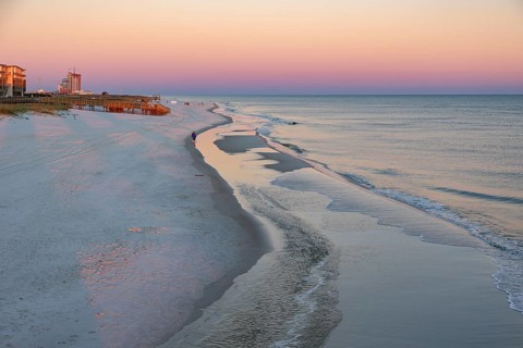 Woman and child walking along the Gulf of Mexico beach as the sun rises over the Gulf of Mexico at