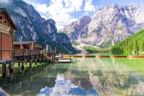 Wooden huts on the lakeshore against a majestic mountain backdrop and calm waters, Lake Braies,