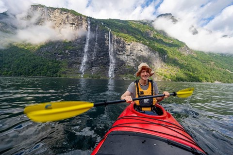 Kayak trip on the Geirangerfjord at the waterfall The Seven Sisters, Young man paddling in a kayak,