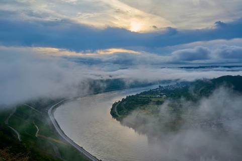 A river winds through misty mountains while the sun illuminates the sky, summer, Rhine bend