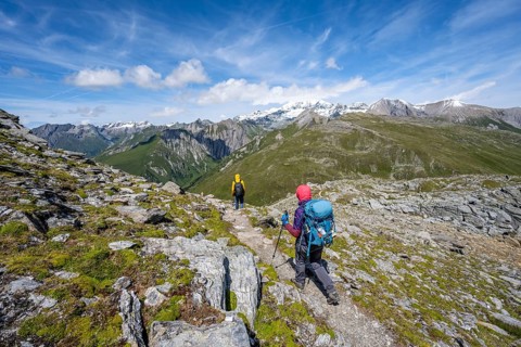 Mountaineers on a hiking trail, view of picturesque mountain landscape with snow-covered summit of