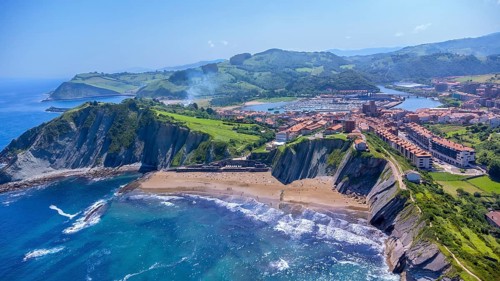 Breathtaking aerial perspective of zumaia's dramatic cliffs, golden beaches, and charming town