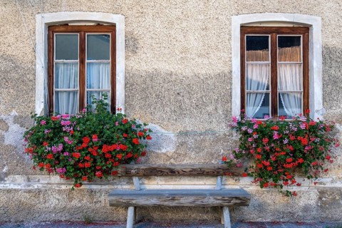 Two windows with flower boxes and wooden bench on a charming stone wall, Umrathshausen, Bavaria,
