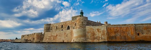 Castello Maniace, sea fortress Maniace, ancient fortress with lighthouse in front of a cloudy sky,