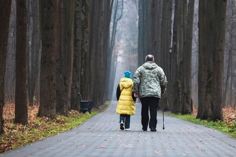Grandfather and granddaughter walking together in the park