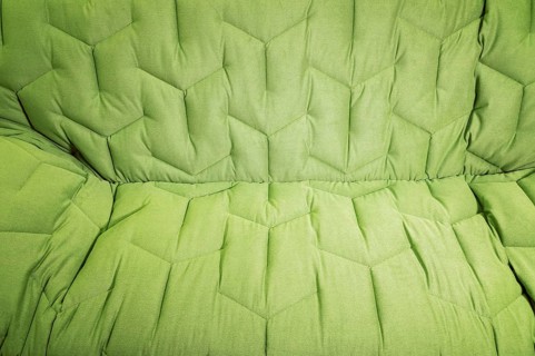 Close-up comfortable green soft sofa with curly stitching. Modern design